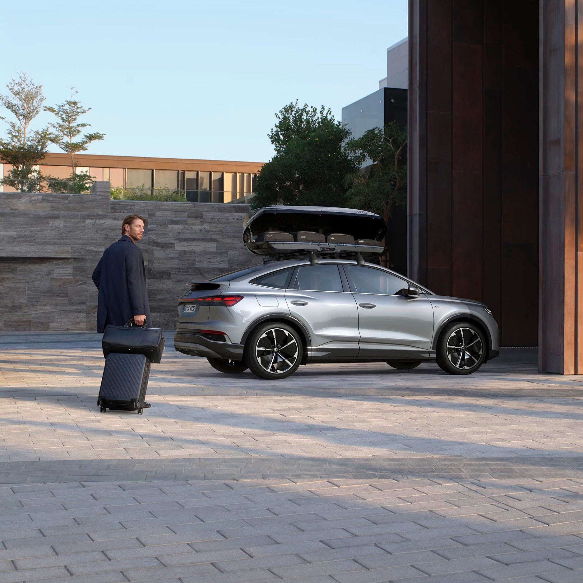 Audi Q4 e-tron sedd från sidan, bakom kommer en person med resväska gåendes